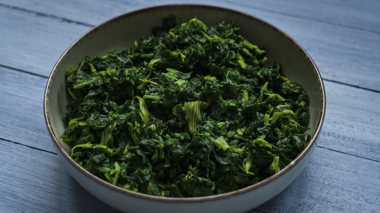 Sauteed spinach leaves in stoneware bowl.