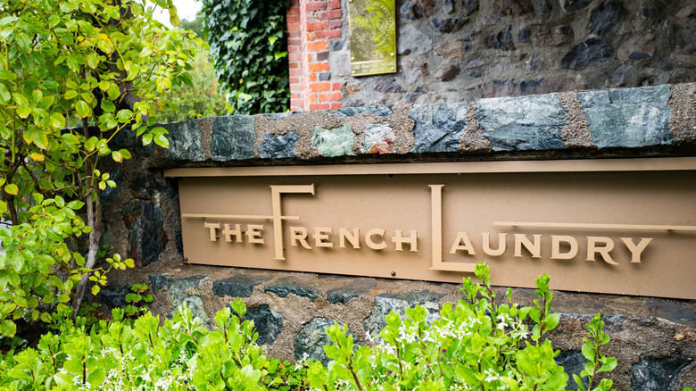 signage for The French Laundry amidst foliage and a stone wall
