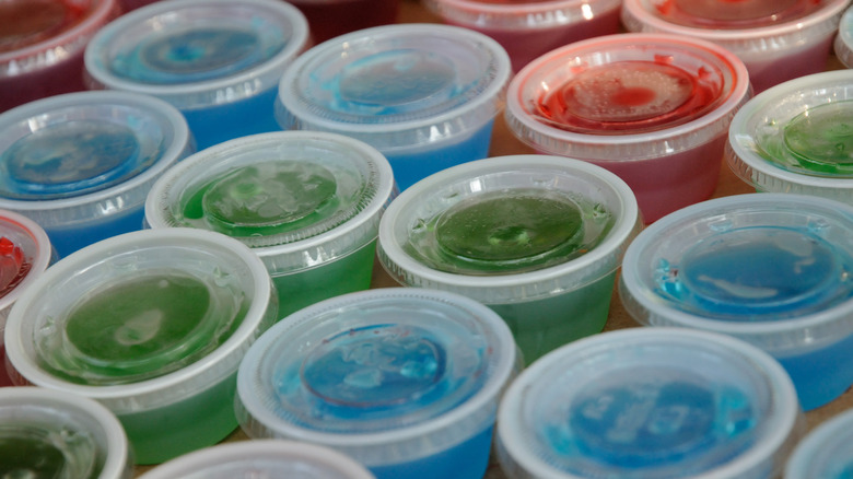 blue, green, and red Jell-O shots in plastic cups