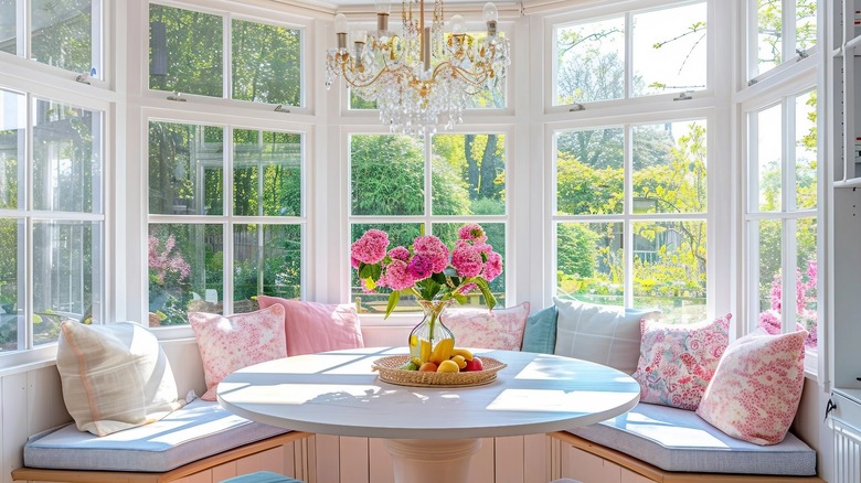 A beautiful, bright and airy breakfast nook is backed by walls of windows