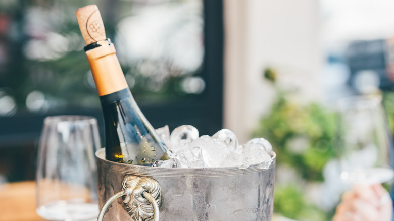 An ice bucket contains an uncorked bottle of wine.