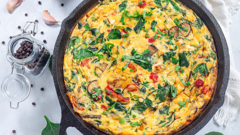 A flavorful-looking frittata with a blend of colorful ingredients served in a cast iron pan