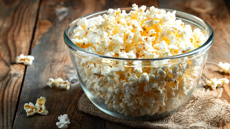 Popcorn in a glass bowl on a folded burlap cloth on a wooden table