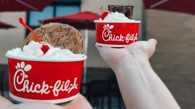 outstretched hands holding Chick-fil-A ice cream sundaes