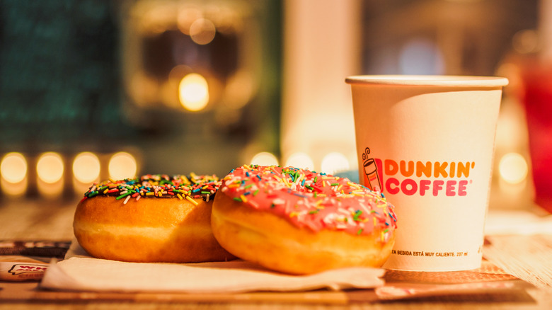 Two Dunkin' donuts with a cup of coffee