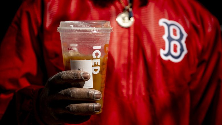 Person holding a Dunkin' cup while wearing a Boston Red Sox shirt