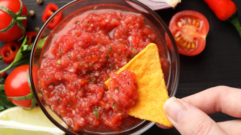 a nacho chip being dipped into salsa
