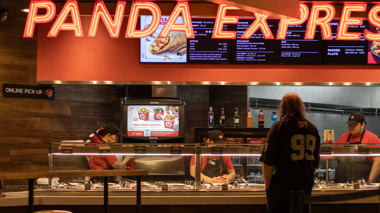 Inside of Panda Express with menu on wall and customer buying food