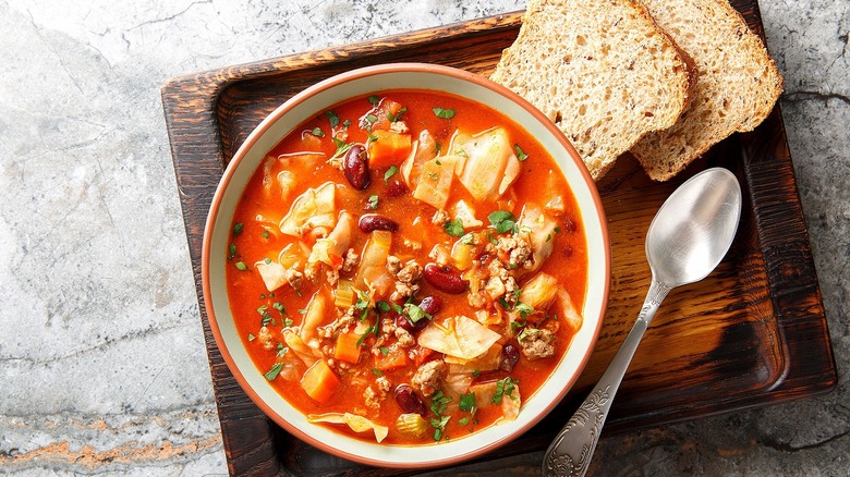 Cabbage soup with ground beef and red kidney beans in a white bowl