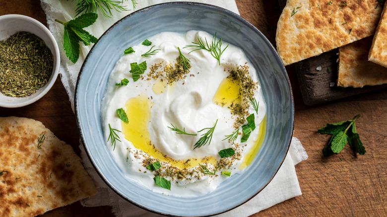 A white dip is stylishly topped with oil and herbs.