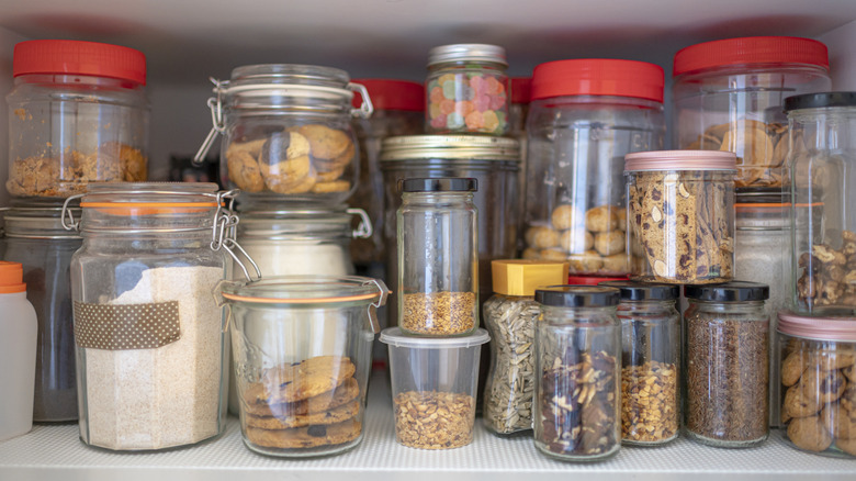 Foodstuffs are stored in glass jars in a pantry.