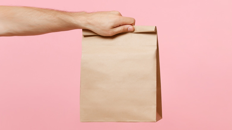 arm holding brown paper bag