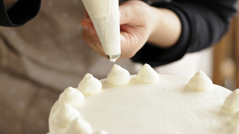 piping frosting onto a cake with a pastry bag