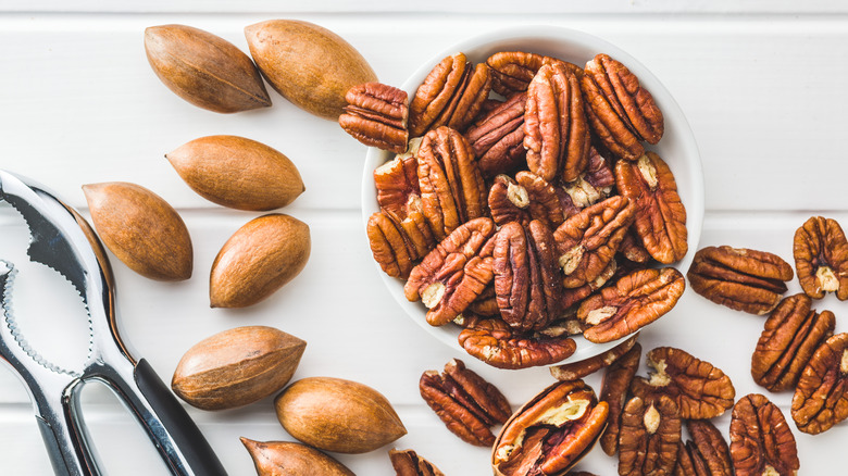 Peeled pecan nuts in bowl on a white table.
