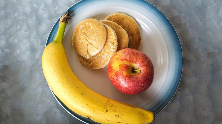 Plate of small pancakes with a whole apple and whole banana