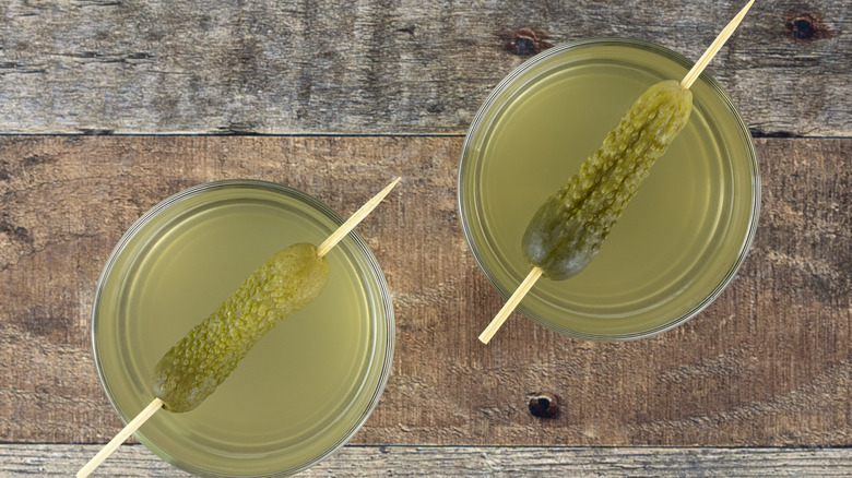 Shots of pickle juice garnished with gherkins