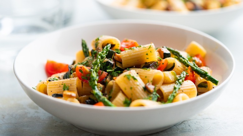 Pasta salad with fresh veggies in a white bowl.
