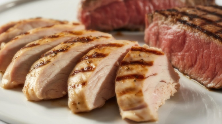 Sliced chicken and steak on a plate.