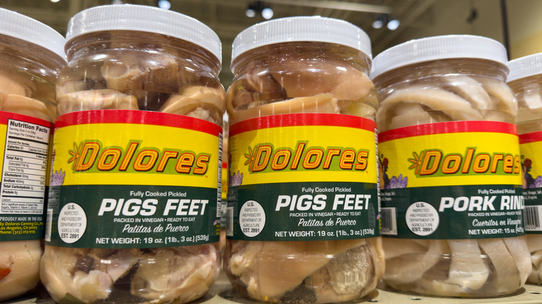 Jars of pickled pigs feet on a supermarket shelf.