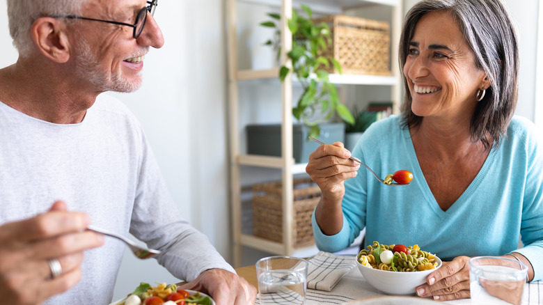 Couple eating pasta bowls with vegetables