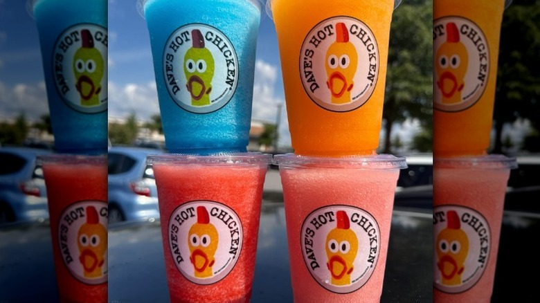 Various flavors of Dave's Hot Chicken slushers stacked outside on top of a car