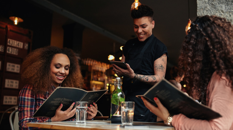 People are seen holding menus and ordering from a restaurant server.
