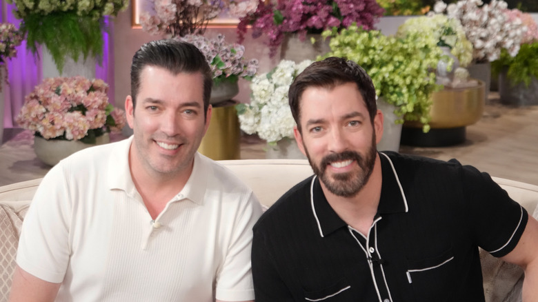 Property brothers on couch with flowers behind them