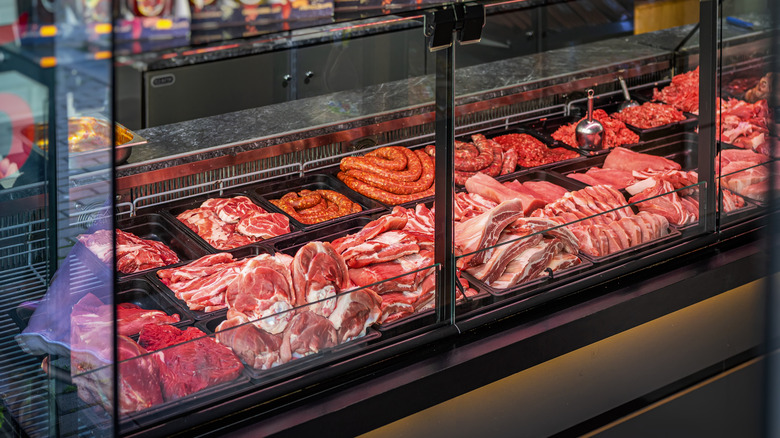 A meat counter displays several protein varieties behind glass.