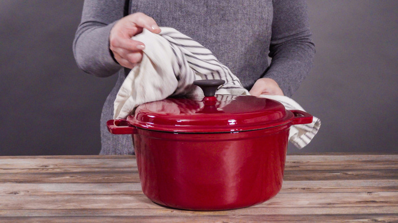A woman holding a cast iron Dutch oven.