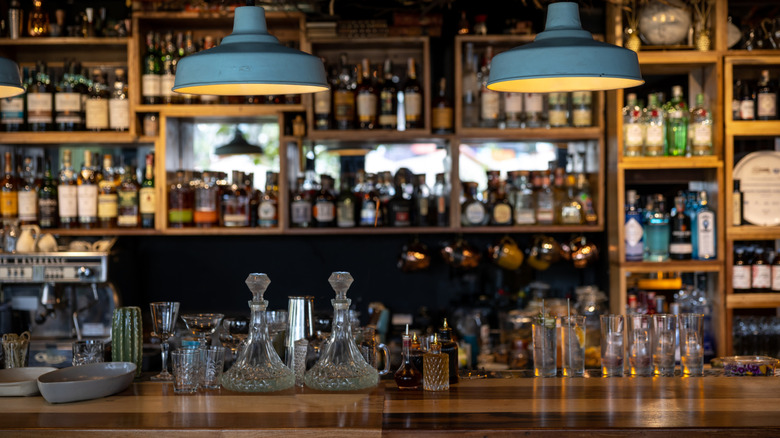 A cozy bar with many liquor bottles against a mirror backdrop