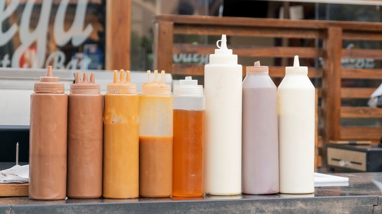 Plastic squeeze bottles with sauces on counter.
