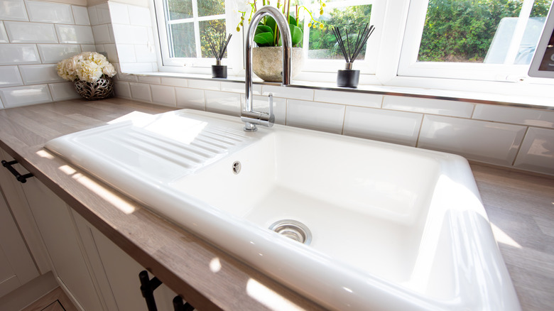 white enameled kitchen sink near a window