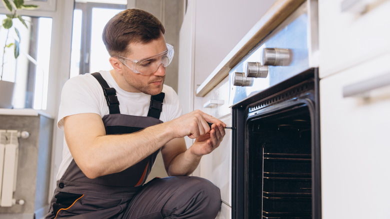 A man screwing in bolts to an oven