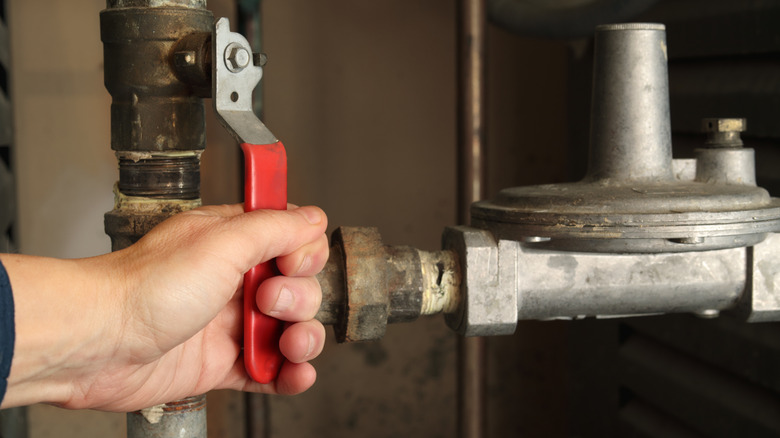A man's hand turning a shut off valve