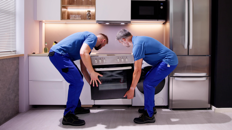 Two men installing an oven into a home