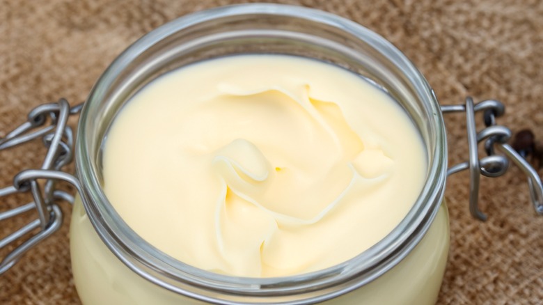 A glass crock of beef tallow with indentations on surface where someone dipped in a utensil