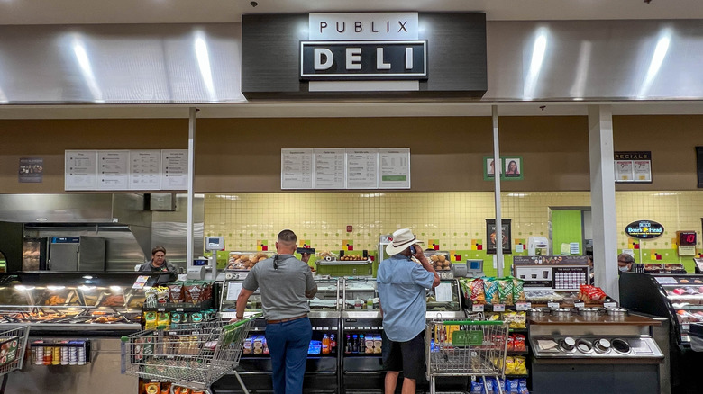 Publix deli counter with two men on phones waiting for order.