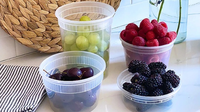 Four Cassandra's Kitchen plastic storage containers filled with various fruits