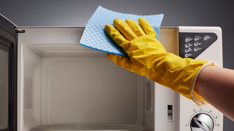 A person wiping a microwave