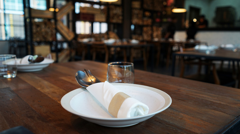 A plate set on a wooden table inside a rustic restaurant.