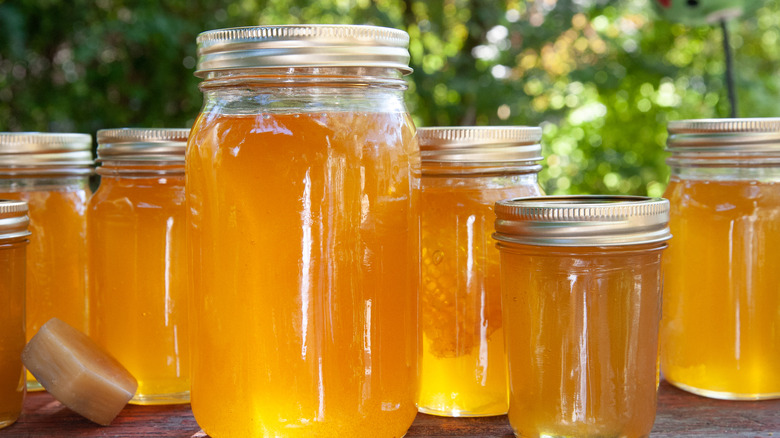 Multiple fresh jars of honey on a table outdoors