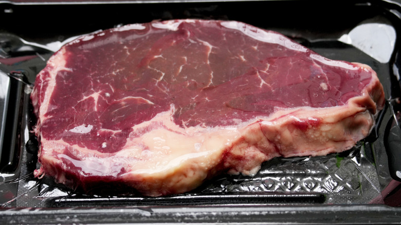 Steak defrosting on a plastic tray