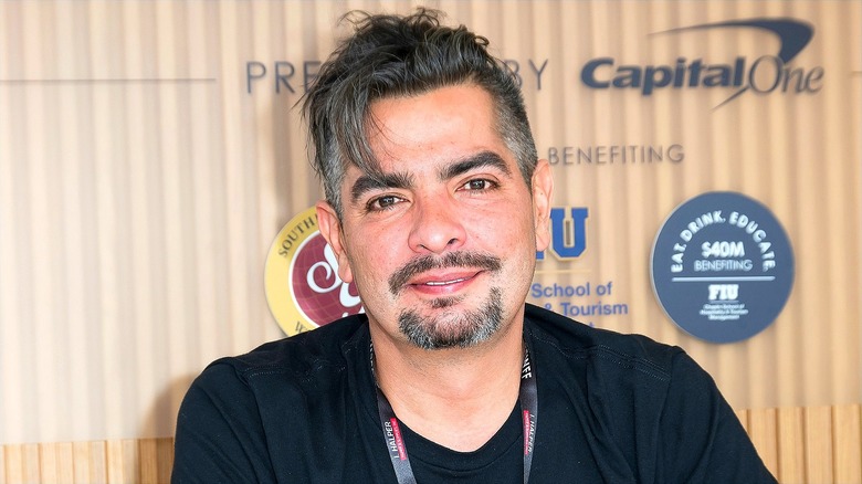 Chef Aarón Sánchez smiling while wearing a black t-shirt and lanyard