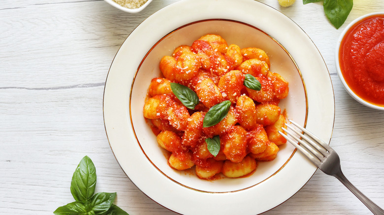 Bowl of gnocchi with marinara sauce and basil leaves