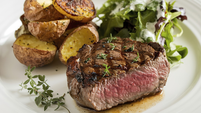 Steak and potatoes together with greens on a plate