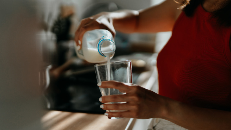 Person pouring milk into glass