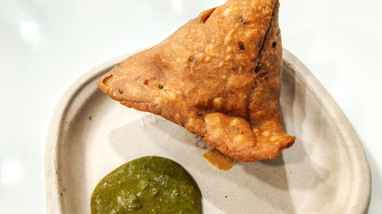 Samosa with green chutney on a plate