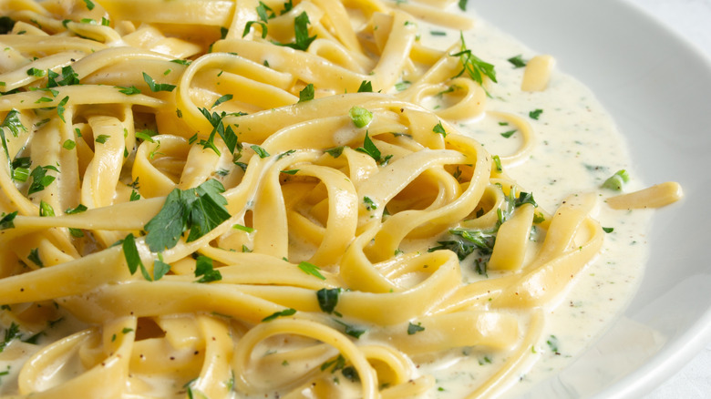 A plate of fettuccine alfredo garnished with parsley