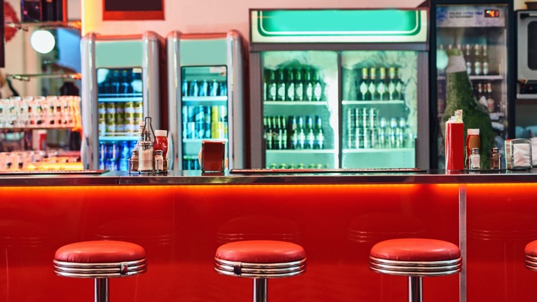 A typical American diner counter with red stools in front of it.