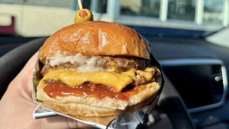Someone holds the Galley Burger from Swensons Drive-In restaurant